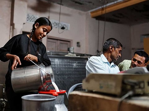 A girl pours milk into a container at a milk collection centre on the outskirts of Jaipur, India, February 23, 2023. 