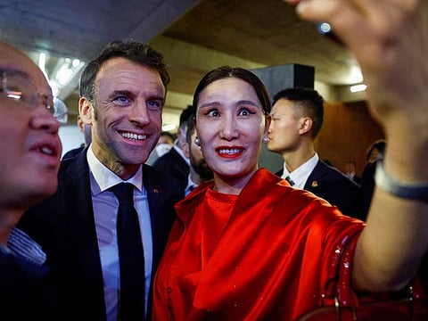 French President Emmanuel Macron takes pictures with attendees at the Red Brick Museum in Beijing, China, April 5, 2023. 