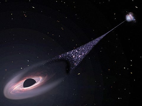 In this illustration released by NASA on April 7, 2023, an artist's impression depicts a runaway supermassive black hole that was ejected from its host galaxy as a result of a tussle between it and two other black holes. This illustration is based on Hubble Space Telescope observations of a 200,000-light-year-long "contrail" of stars behind an escaping black hole. 