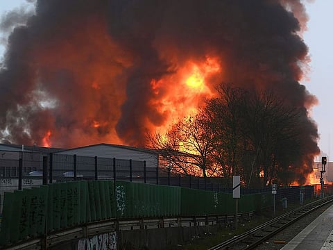 Huge flames rise from a fire in Hamburg, Germany, Sunday April 9, 2023. Police warned people in Hamburg to close their windows early on Easter Sunday after a large fire that engulfed several warehouses sent black, chemical-laden smoke drifting over the city. 