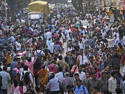 A crowd walks in a market area outside Dadar station in Mumbai, India, Friday, March 17, 2023. 
