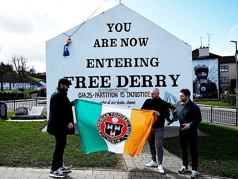 People hold a flag with an Irish tricolour in front of Free Derry Corner on the 25th anniversary of the Good Friday Agreement peace deal, in Londonderry, Northern Ireland April 10, 2023. 