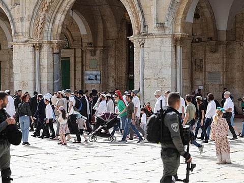 Jewish visitors walk protected by Israeli security forces at the Al Aqsa mosque compound in Jerusalem on April 9, 2023.