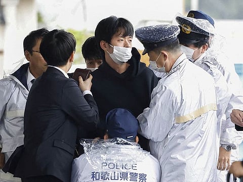 A man, believed to be a suspect who threw an apparent smoke bomb at Japanese Prime Minister Fumio Kishida during his outdoor speech, is held by police officers at Saikazaki fishing port in Wakayama, Wakayama Prefecture, south-western Japan April 15, 2023, in this photo released by Kyodo. 