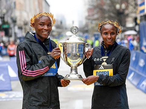 Evans Chebet of Kenya (left) and Hellen Obiri of Kenya (right) pose with the winner's trophy in the 2023 Boston Marathon. 