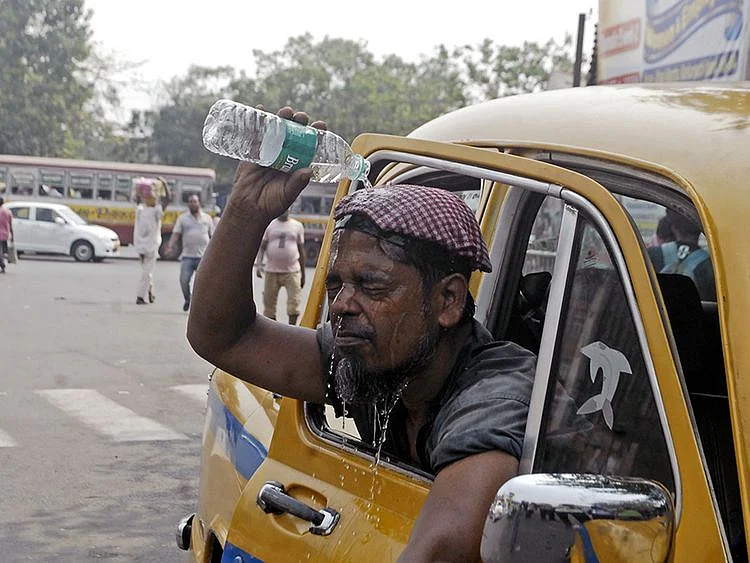  A taxi driver pours water over his face to beat the heat during a hot summer afternoon, in Kolkata on Tuesday. 