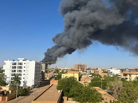 A column of smoke rises behind buildings near the airport area in Khartoum on April 19, 2023, amid fighting between the army and paramilitaries following the collapse of a 24-hour truce.  