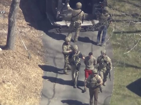 This image made from video provided by WCVB-TV, shows Jack Teixeira, in T-shirt and shorts, being taken into custody by armed tactical agents on Thursday, April 13, 2023, in Dighton, Mass.
