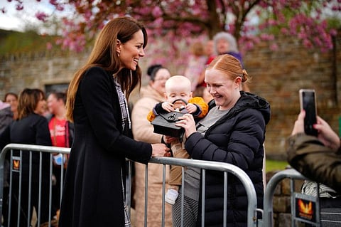 Lucy Williams, from Aberfan, holds her son Daniel Williams, one, as he takes the handbag of Catherine, Princess of Wales, during her visit with her husband the Prince of Wales, on Friday to the Aberfan memorial garden, to pay their respects to those who lost their lives during the Aberfan disaster on October 21, 1966.