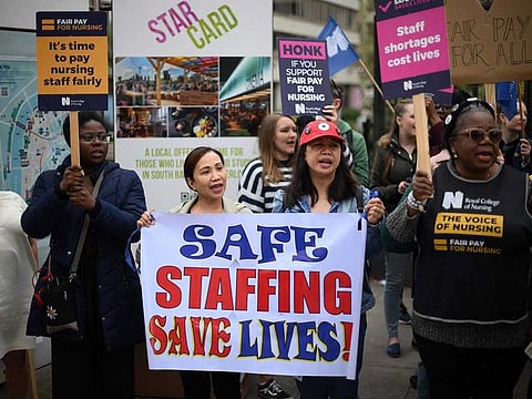 Healthcare workers hold placards as they demonstrate outside St Thomas' Hospital in London on May 1, 2023, as members of Unite and the Royal College of Nursing (RCN) continue their industrial action.  