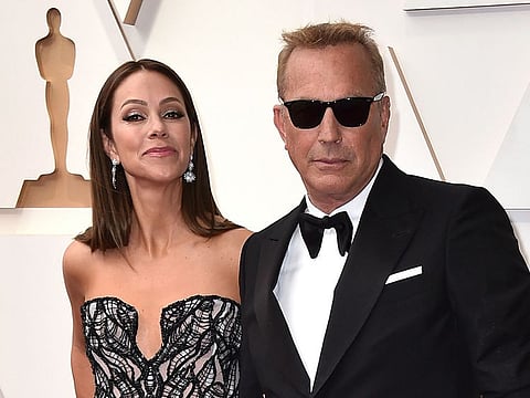 Christine Baumgartner, left, and Kevin Costner arrive at the Oscars, March 27, 2022, at the Dolby Theatre in Los Angeles.