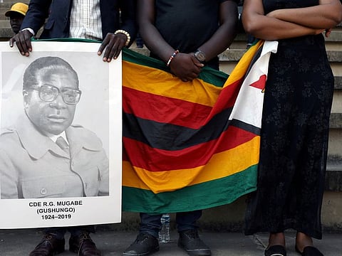 Mourners hold a poster during the state funeral of Zimbabwe's longtime ruler Robert Mugabe at a national sports stadium in Harare, Zimbabwe, September 14, 2019.