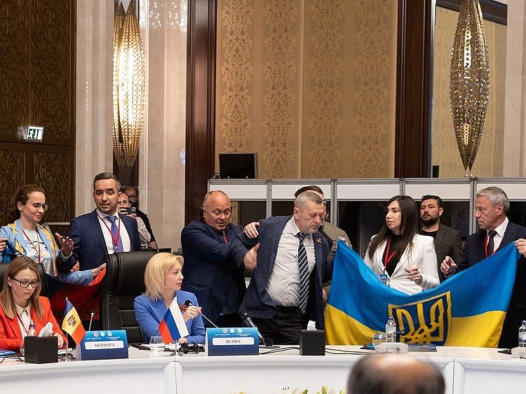 Members of Ukrainian delegation unfurl their national flag next to Olga Timofeeva, deputy head of Russian delegation, to disrupt her speech during a meeting of the Parliamentary Assembly of the Black Sea Economic Cooperation (PABSEC) in Ankara, on May 4, 2023. 