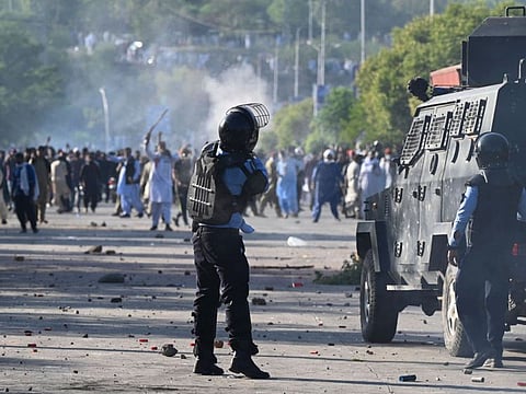 A policeman fires a teargas shell towards Pakistan Tehreek-e-Insaf (PTI) party activists of Khan during a protest outside the police headquarters where Khan is in custody, in Islamabad on May 10, 2023.  