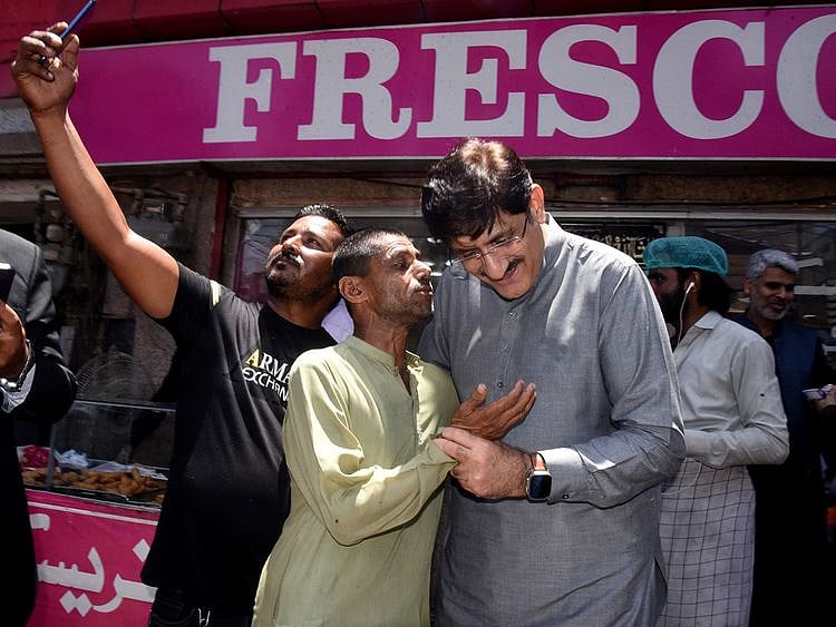 CM interacts with a common man outside a bakery as another citizen takes a selfie with him in Karachi to oversee security situation.