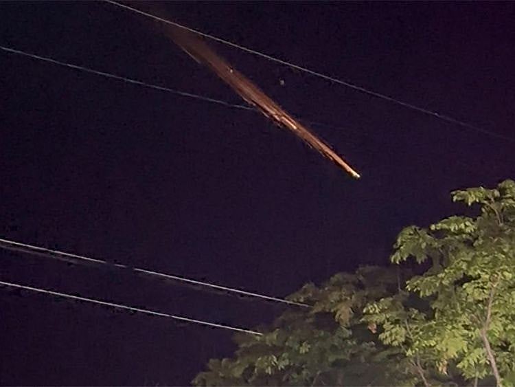 This video grab taken from video footage recorded on May 10, 2023 and released to AFP courtesy of Twitter user 'shokosan' shows fiery streaks of light across the night sky at an unconfirmed location in the Japanese islands of Okinawa.  