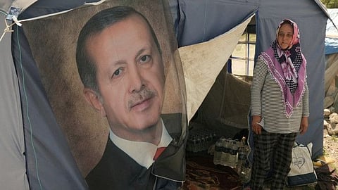  Ayse Kekec, an earthquake survivor living in a tent with her son, stands in front of their tent with a poster of Turkish President Erdogan on it, in Kahramanmaras, Turkey May 11, 2023.  