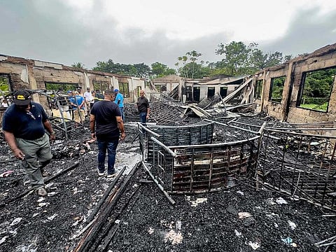Investigators and government employees inspect the school dormitory where a fire killed at least 20 people in Mahdia, Guyana on May 22, 2023. 