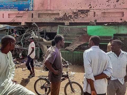 People walk past a medical centre building riddled with bullet holes at the Souk Sitta (Market Six) in the south of Khartoum on June 1, 2023. Shelling and aerial bombardments killed 18 civilians at a market in Sudan's capital where fighting showed no signs of abating on June 1, after the army abandoned truce talks.