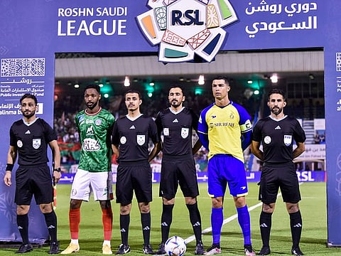 Nassr's Portuguese forward and team captain Cristiano Ronaldo (2nd R) and Ettifaq's Saudi midfielder and team captain Ali Hazazi (2nd L) pose for a picture with the referee team ahead of the Saudi Pro League football match between Al Nassr and Al Ettifaq at the Prince Mohammed Bin Fahd Stadium in Dammam on May 27, 2023. 