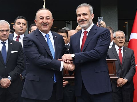 Turkey's newly appointed Foreign Affairs Minister Hakan Fidan (R) and his predecessor Mevlut Cavusoglu shake hands during a handover ceremony in Ankara on June 5, 2023. The Turkish president unveiled a new cabinet lineup on June 3 after winning a historic runoff election to serve a third term in office.