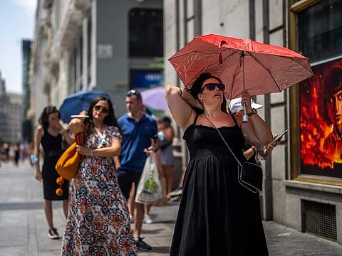 A woman holds an umbrella to shelter from the sun during a hot sunny day in Madrid.