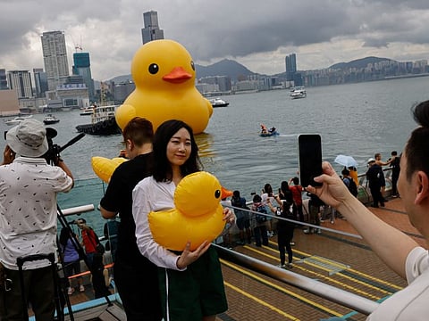 People take photos of an art installation, dubbed "Double Ducks" by Dutch artist Florentijn Hofman, which is seen at Victoria Harbour, in Hong Kong, on June 9, 2023.  