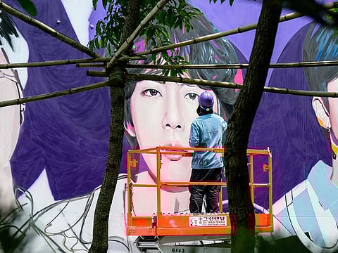An artist spray paints a mural of K-pop megastars BTS in Seoul on June 12, 2023, on the occasion of the supergroup's 10-year anniversary. Fans of K-pop megastars BTS flocked to hotspots around Seoul on June 12 to mark the supergroup's 10-year anniversary, with South Korea unveiling a special commemorative stamp series to celebrate.       