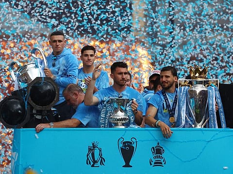 Manchester City's Phil Foden celebrates with the Champions League trophy as Aymeric Laporte celebrates with the FA Cup trophy and Ruben Dias celebrates with the Premier League trophy during the Manchester City Victory Parade in Manchester.