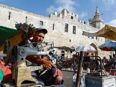 A Palestinian tailor sews a bag in front of Qalaat Barquq, in Khan Younis in the southern Gaza Strip June 10, 2023. 