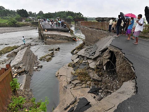 People stand on a damaged bridge over the Daranga River after flash floods washed away a section of it following monsoon rains in Kumarikata village of Baska district, some 52 Km from Guwahati in India's Assam state on June 23, 2023.  
