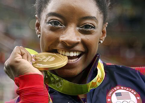 United States' Simone Biles bites her gold medal for the artistic gymnastics women's individual all-around final at the 2016 Summer Olympics in Rio de Janeiro.
