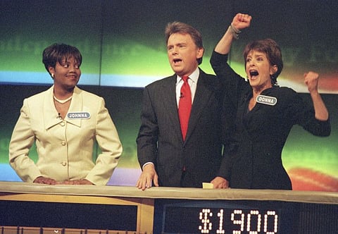Johnna Goodwin watches as Donna Handel, right, reacts after winning on 'Wheel of Fortune', with host Pat Sajak during a taping of the game show in 1999.