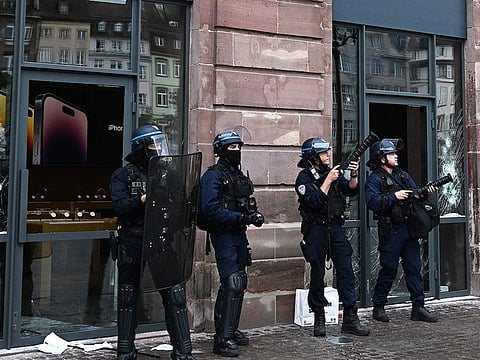  French police officers with tear gas canister launchers next to the facade of a damaged Apple Store at Place Kleber, in Strasbourg, eastern France, on June 30, 2023.