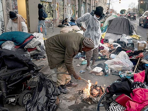 Robert Mason, a 56-year-old homeless man, warms up a piece of doughnut over a bonfire he set to keep himself warm on Skid Row in Los Angeles. 