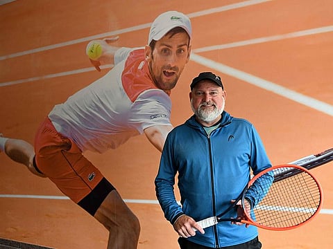 Tennis coach Wolfgang Reiner poses in front of a big photo of Serbian tennis player Novak Djokovic at the tennis center in Oberschleissheim near Munich, southern Germany, on June 23, 2023. 
