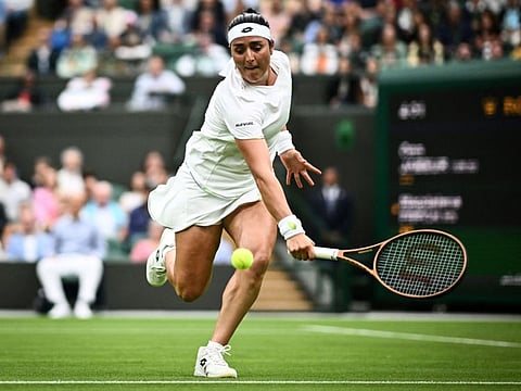 Tunisia's Ons Jabeur plays a backhand return to Poland's Magdalena Frech during their women's singles match in the Wimbledon Championships at The All England Tennis Club in Wimbledon on Tuesday