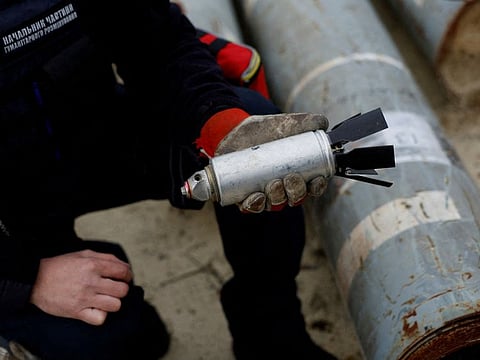 Ukrainian military serviceman Igor Ovcharruck holds a defused cluster bomb from an MSLR missile, among a display of pieces of rockets used by Russian army, that a Ukrainian munitions expert said did not explode on impact, in the region of Kharkiv, Ukraine, October 21, 2022.  