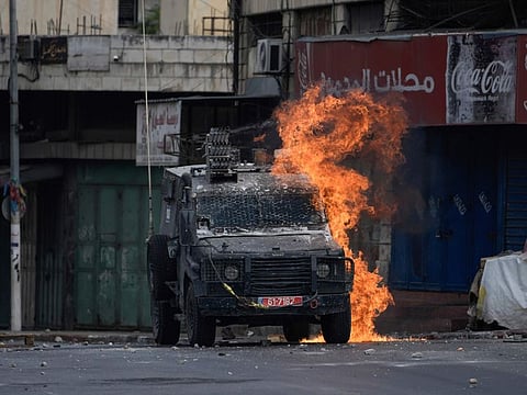 A Molotov cocktail thrown by a Palestinian protester explodes on an Israeli armoured vehicle during clashes with Israeli security forces following a military raid in the West Bank city of Nablus, on July 7, 2023.  