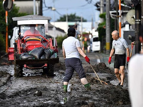 Residents clear silt from a road following flooding in the city of Kurume, Fukuoka prefecture, on July 10, 2023, after heavy rains hit wide areas of Kyushu island. 