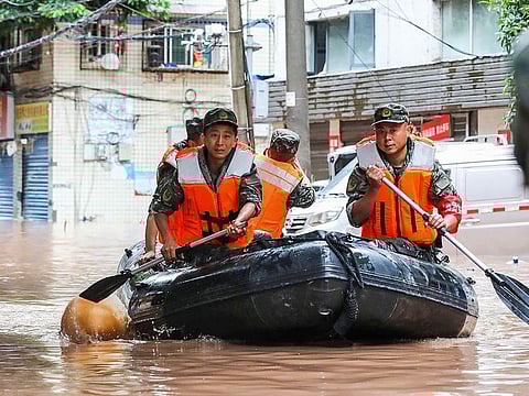 Paramilitary policemen searching an area after it was flooded by heavy rains in China's southwestern Chongqing