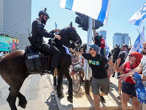 People confront with an Israeli police officer as they demonstrate on 'Day of Disruption' in protest against Israeli Prime Minister Benjamin Netanyahu and his nationalist coalition government's judicial overhaul, in Tel Aviv on July 11, 2023.  