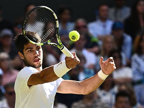 Spain's Carlos Alcaraz returns the ball to Denmark's Holger Rune during their men's singles quarter-finals tennis match on the tenth day of the 2023 Wimbledon Championships at The All England Lawn Tennis Club in Wimbledon, southwest London, on July 12, 2023.