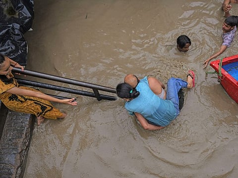 Residents move towards a safer place as the water level of the Yamuna river rose to a record level in the Yamuna Bazar area of New Delhi on Wednesday.  
