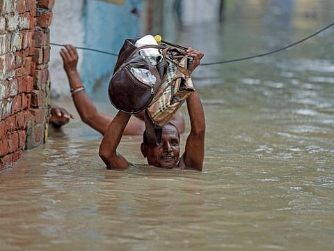 Residents move towards a safer place as the water level of the Yamuna river rose to a record level in the Yamuna Bazar area of New Delhi on Wednesday.  