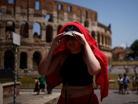 A woman shelters from the sun with a shirt near the Colosseum during a heatwave across Italy.