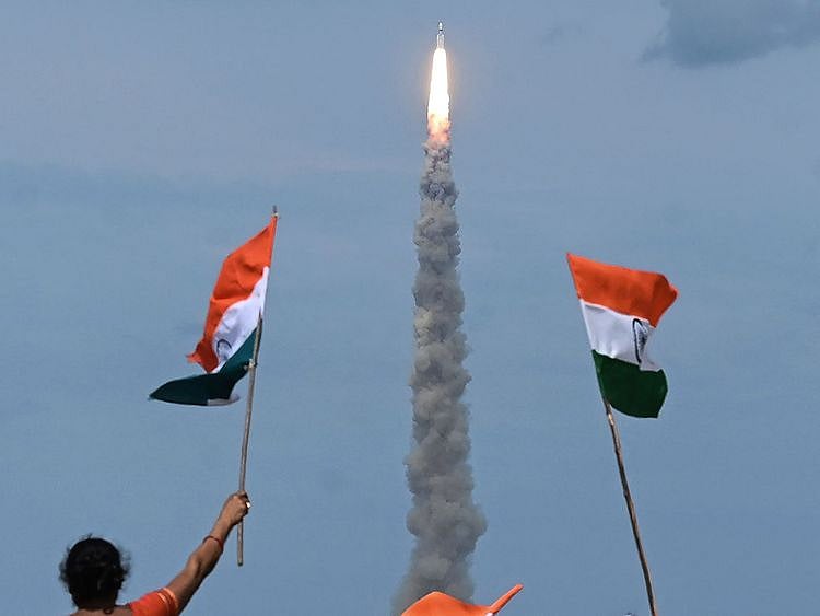 People wave Indian flags as an Indian Space Research Organisation (ISRO) rocket carrying the Chandrayaan-3 spacecraft lifts off from the Satish Dhawan Space Centre in Sriharikota, an island off the coast of southern Andhra Pradesh state on July 14, 2023.  