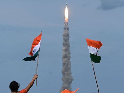 People wave Indian flags as an Indian Space Research Organisation (ISRO) rocket carrying the Chandrayaan-3 spacecraft lifts off from the Satish Dhawan Space Centre in Sriharikota, an island off the coast of southern Andhra Pradesh state on July 14, 2023.  