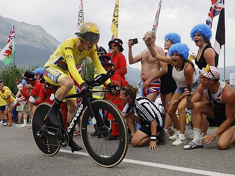 Team Jumbo–Visma's Jonas Vingegaard wearing the yellow jersey in action during stage 16 as spectators cheer on.