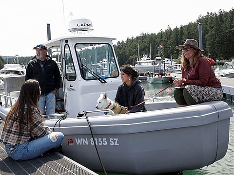 Dr. Deborah Giles (R), a resident scientist at the University of Washington's Friday Harbor Laboratories, and director of the Wild Orca conservation research organization, sits on her boat with dog Eba, and talks with visitors while moored in Snug Harbor on San Juan Island, Washington.